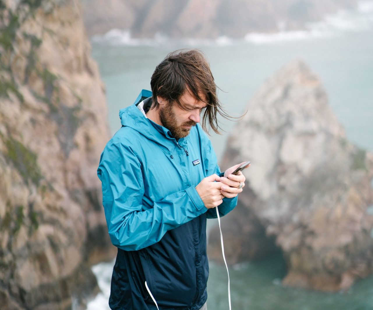 focused-man-with-smartphone-on-cliff-4330271-e1594378129507